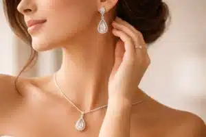 How to Style Jewelry | Close-up of a bride wearing a large teardrop diamond earring and matching pendant necklace, softly lit in natural light against a neutral background.