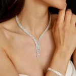 Budget Jewellery | Close-up of a bride wearing a silver-tone crystal zircon Y-shaped necklace with matching drop earrings and bracelet, in a strapless white dress, hand near chin.